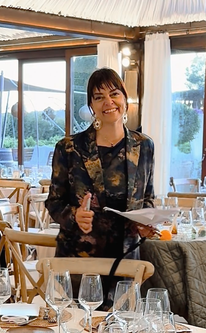 Smiling woman with notepad standing among decorated tables at an elegant venue in Ibiza—professional event and wedding planning content by vIBZ Marketing