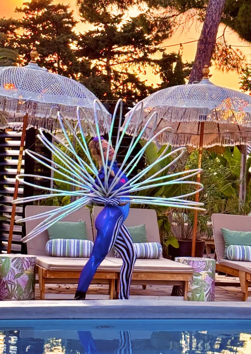 Performer in futuristic costume with hoops on stage at sunset in Ibiza—creative event entertainment content by vIBZ Marketing.