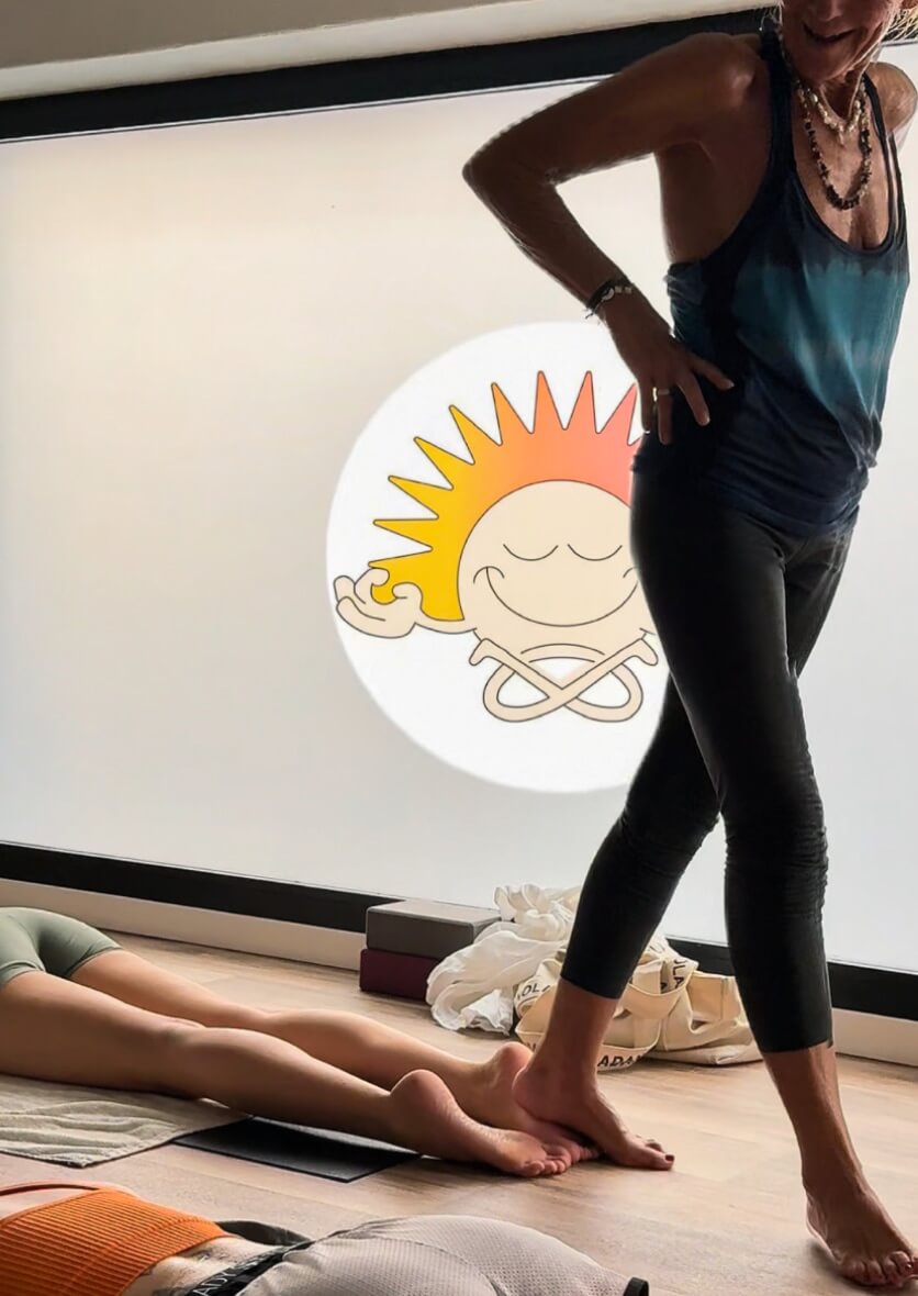 Yoga instructor guiding a relaxation class in Ibiza studio with sun logo—wellness and mindful lifestyle content creation by vIBZ Marketing 