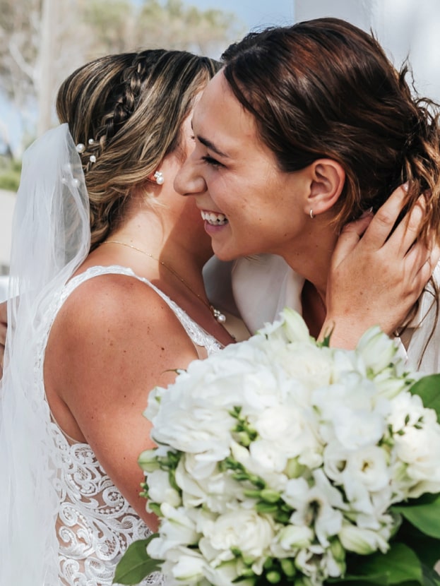 Bride and content creator sharing a joyful hug with bouquet in hand—content creation in Ibiza by vIBZ Marketing.